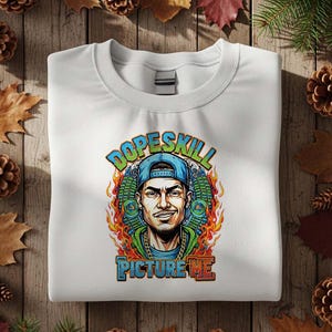 May include: White crew neck sweatshirt with a graphic of a man wearing a blue cap and gold chain. The graphic includes the text "Dopeskill" above the image and "Picture Me" below, with flames and green accents.
