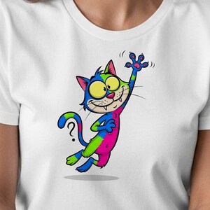Puede incluir: Camiseta blanca con un diseño de gato de dibujos animados colorido. El gato está representado en azul, verde y rosa, con ojos amarillos y un signo de interrogación en la cola. Ilustración alegre y caprichosa.