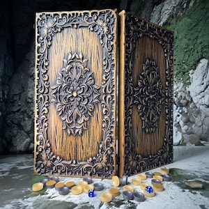 May include: A wooden backgammon set with intricate, carved floral designs on the exterior. The set is a warm brown color with dark brown accents. The game pieces are scattered around the set, with a few dice visible.