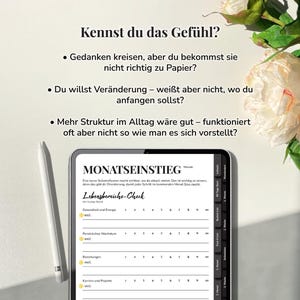 Pu&ograve; includere: Un tablet digitale che mostra un pianificatore mensile intitolato "MONATSEINSTIEG", con sezioni per il monitoraggio delle aree della vita. Uno stilo bianco &egrave; accanto al tablet. L'immagine include testo in tedesco e una composizione floreale.