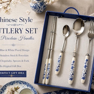 Puede incluir: Un juego de cubiertos de estilo chino en una caja de regalo azul. El juego incluye palillos, cucharas y un tenedor. Los utensilios de acero inoxidable tienen mangos de porcelana con un diseño floral azul y blanco. El texto "CUTLERY SET" es visible.