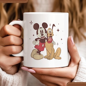 Peut inclure: Mug en céramique blanche avec Mickey Mouse et Pluto. Mickey porte un short rouge et Pluto est beige. Le mug porte les mentions "LUXURY CERAMIC" et "FADE-RESISTANT PRINT".