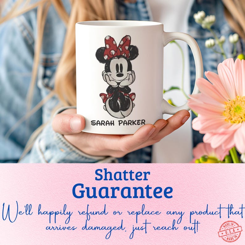May include: White ceramic mug featuring a Minnie Mouse design with a red bow and dress. The name "SARAH PARKER" is printed below the character. The mug has a curved handle and is held in front of a floral background.