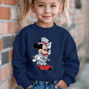K&ouml;nnte beinhalten: Marineblaues Sweatshirt mit Mickey Mouse als Zauberer. Mickey tr&auml;gt einen grauen Anzug, eine rote Fliege, rote Schuhe und einen Zylinder. Das Sweatshirt ist einfarbig mit einem Rundhalsausschnitt.