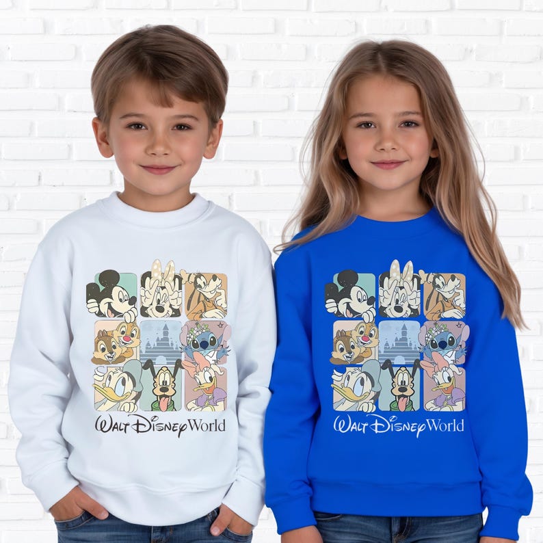 May include: Two children wearing sweatshirts. One is white, the other is blue. Both sweatshirts feature a grid of Disney character illustrations and the text "Walt Disney World" in black script.