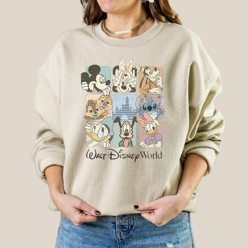 May include: Beige sweatshirt featuring a colorful grid of Disney characters including Mickey Mouse, Minnie Mouse, Pluto, Chip and Dale, Stitch, Donald Duck, and Goofy. The words "Walt Disney World" are printed below the grid in a script font.