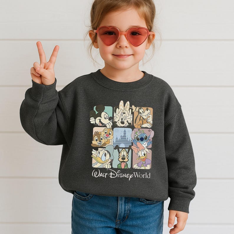 May include: Dark gray sweatshirt featuring a grid of Disney character illustrations, including Mickey Mouse, Minnie Mouse, and Stitch. The words "Walt Disney World" are printed below the grid. The sweatshirt is worn by a child.