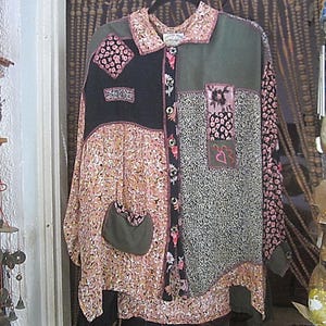 May include: A long-sleeved patchwork shirt with a button-up front. The shirt is made of a variety of fabrics in shades of pink, green, and black. The fabric has a floral pattern and is decorated with embroidered details.