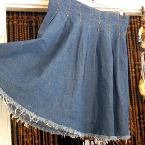 May include: A blue denim skirt with a frayed hem and a row of silver studs along the waistband.