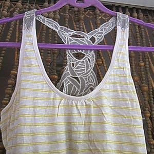 May include: A white and yellow striped tank top with a white lace overlay. The lace overlay is in the shape of a large, intricate design.
