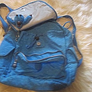 May include: A white ceramic mug with a black handle and the text "But First, Coffee" in a bold, black font. The mug is set against a blurred background, suggesting a cozy setting.