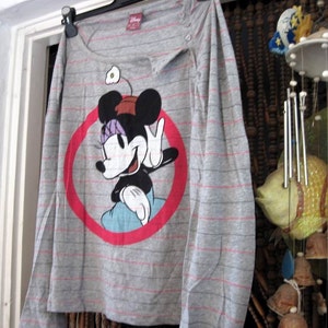 May include: Gray long-sleeved shirt with a red circle and a cartoon image of Mickey Mouse wearing a purple bow. The shirt has thin gray stripes.