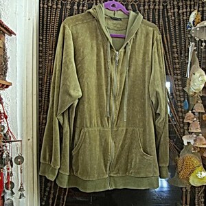 May include: A green velour hooded jacket with a zip closure and two front pockets. The jacket is hanging on a purple hanger in front of a beaded curtain.