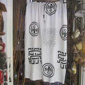 May include: White skirt with a black geometric pattern. The pattern features repeating symbols and designs.