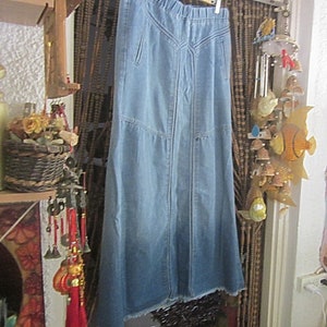 May include: A long denim skirt with a frayed hem. The skirt has a straight silhouette and a high waist.