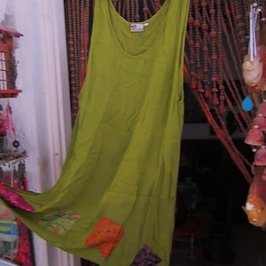 May include: A green sleeveless dress with a scoop neck and a patchwork design. The dress has a long, flowing skirt and is made of a lightweight fabric.