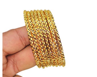 May include: A set of six gold-colored bangles featuring a repeating diamond-shaped cross-hatch texture across the entire surface of each circular band. The bangles are arranged in a parallel stack, showcasing a bright, reflective metallic finish.