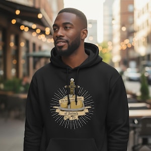 May include: Black hooded sweatshirt with a graphic design featuring a cross, a crown, and the text "The Holy Hand Grenade of Antioch". The design is in gold and white, with a sunburst effect.