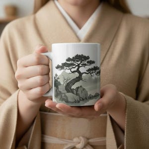 May include: White ceramic mug featuring a black and gray illustration of a bonsai tree on a rocky landscape. The design evokes a serene, minimalist aesthetic, perfect for enjoying coffee or tea.