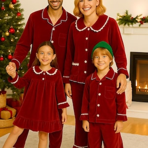 Peut inclure: Une famille de quatre personnes portant des pyjamas en velours rouge assortis avec des bordures blanches. Les pyjamas comprennent des chemises à manches longues et des pantalons, et une chemise de nuit pour la fille. Un sapin de Noël et une cheminée sont en arrière-plan.