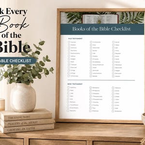 Op de afbeelding: Een ingelijste, printbare checklist getiteld Books of the Bible Checklist, met kolommen voor de boeken van het Oude en Nieuwe Testament met selectievakjes. Het document staat in een houten lijst naast een vaas met groen en boeken.