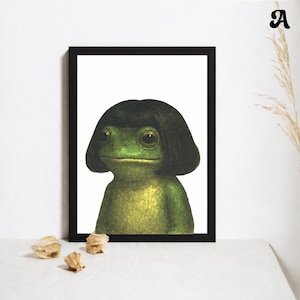 May include: A framed art print featuring a whimsical illustration of a frog with a black wig. The frog is green with a yellow underbelly, set against a white background. The frame is black, and the artwork is displayed on a white surface.