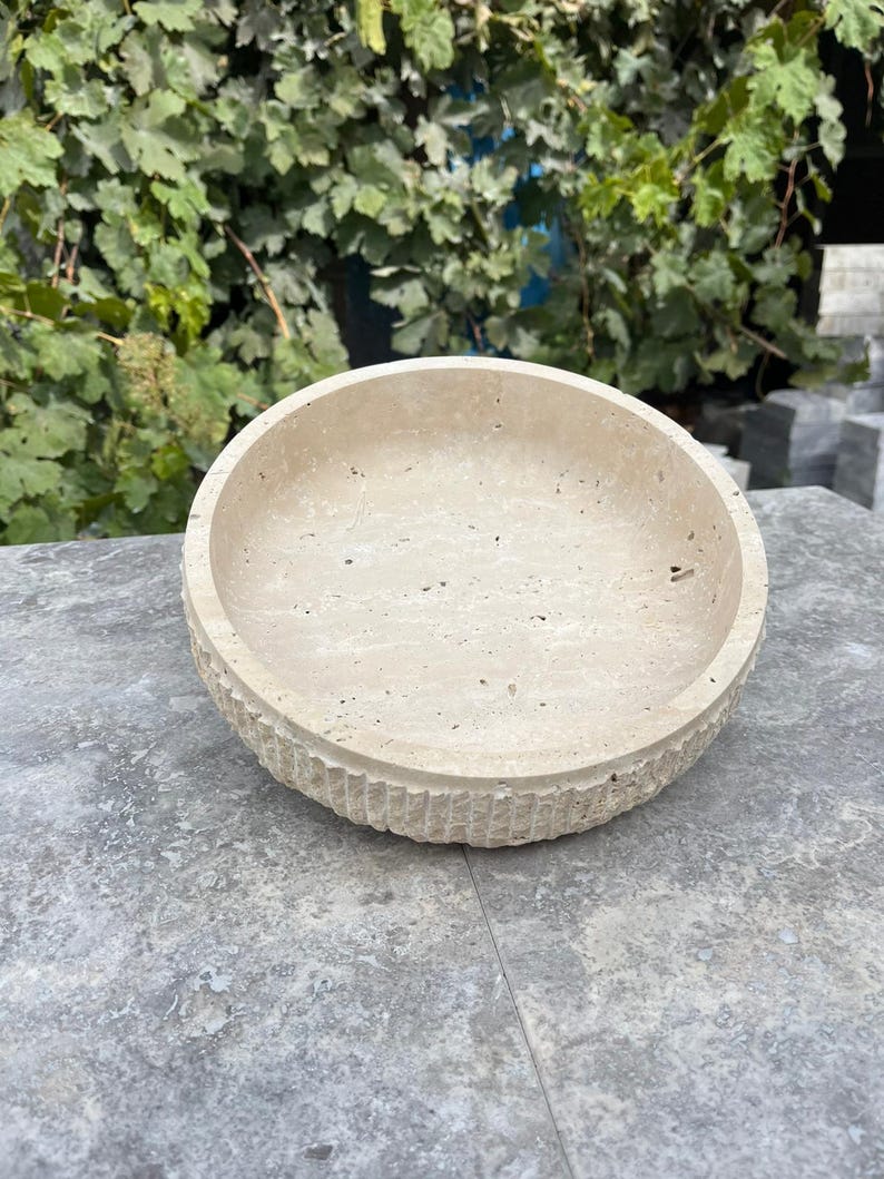 K&ouml;nnte beinhalten: Eine beige, runde Steinschale mit strukturierter Au&szlig;enseite und glatter Innenseite. Die Schale besteht aus einem hellfarbigen Stein und hat ein schlichtes, aber elegantes Design. Die Schale eignet sich f&uuml;r dekorative oder funktionale Zwecke.
