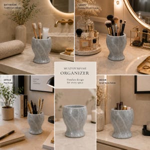 May include: A grey marble-patterned multipurpose organiser with a flared base and a wide, circular opening. The cylindrical container features a smooth, polished finish with subtle white veining throughout, suitable for holding brushes, pens, or toiletries.