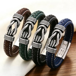 May include: Four leather bracelets in brown, green, black, and blue. Each bracelet features a braided leather band and a silver-colored knot design clasp. The blue bracelet has the text "YOU & ME 14.5.2016" on the clasp.