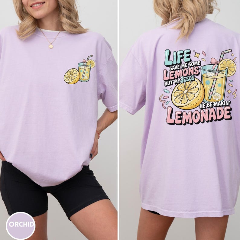 May include: A light purple t-shirt with a lemonade graphic on the front and back. The front features a lemon and a glass of lemonade. The back of the shirt has the text "LIFE gave me some lemons but my Jesus he be makin' lemonade."