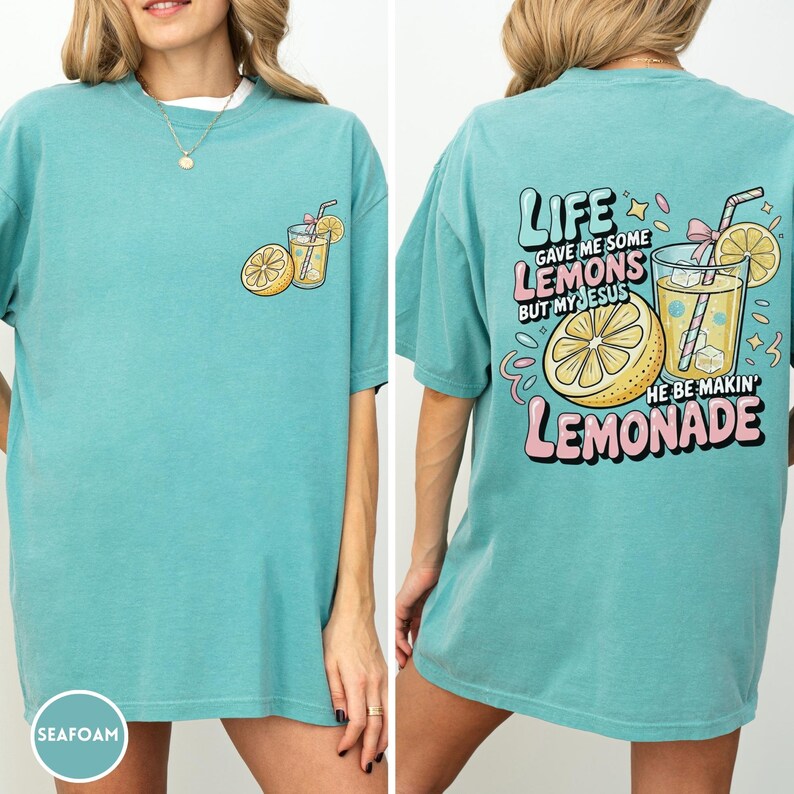 May include: Seafoam green t-shirt with a lemon and lemonade graphic. The front features a lemon and a glass of lemonade. The back of the shirt has the text "LIFE GAVE ME SOME LEMONS BUT MY JESUS HE BE MAKIN' LEMONADE."