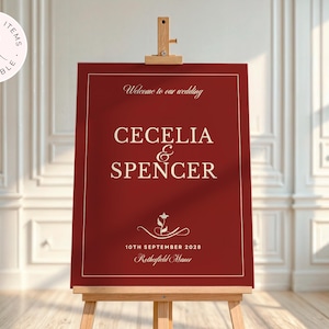 Puede incluir: Un letrero de boda burdeos sobre un caballete de madera. El letrero muestra los nombres CECELIA & SPENCER en escritura blanca, la fecha y el lugar. Las palabras "Welcome to our wedding" est&aacute;n en la parte superior.