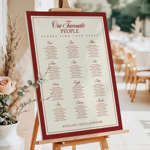 Puede incluir: Un plano de asientos de boda en un caballete. El letrero con marco burdeos tiene un fondo color crema con nombres enumerados bajo los n&uacute;meros del uno al doce. El texto en la parte superior dice "Our Favourite People". El texto inferior dice "With Love, Cecelia & Spencer."
