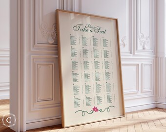 以下が含まれることがあります： 「Please Take a Seat」の文字が緑色の筆記体で書かれた、額入りの座席表。名前がアルファベット順にリストされ、下部に花の模様があります。フレームは薄茶色で、背景はオフホワイトです。