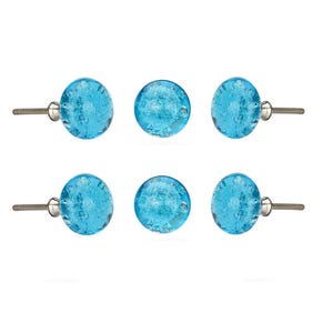 May include: Six round, light blue glass cabinet knobs with a textured, bubbly appearance. Each knob has a silver-colored metal stem for mounting. The knobs are arranged in two rows of three against a white background.