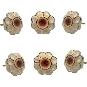 May include: Six flower-shaped cabinet knobs. Each knob features a light pink center, surrounded by white petals with gold trim. The knobs have a gold-colored stem for mounting.