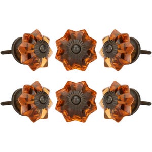 May include: Six amber-colored glass cabinet knobs with a starburst design. Each knob has a dark metal base and screw. The knobs are arranged in two rows of three.