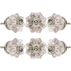 Op de afbeelding: Zes heldere glazen kastknoppen met een stervormig ontwerp. Elke knop heeft een facetvormige, bloemachtige vorm met een zilverkleurige metalen basis en schroef. De knoppen zijn gerangschikt in twee rijen van drie.