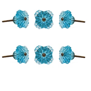 May include: A set of six light blue glass cabinet knobs arranged in two rows of three. Each knob features a faceted, flower-like shape with a central bronze-colored metal screw post extending from the back for mounting purposes.