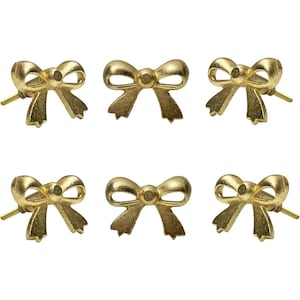 May include: Six gold-colored bow-shaped stud earrings. Each earring features a detailed bow design with a post for piercing. The earrings are arranged in two rows of three.