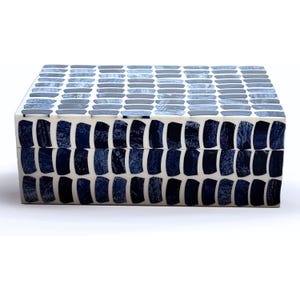 Peut inclure: Boîte décorative rectangulaire avec un motif en mosaïque. La boîte est blanche avec un motif de carreaux rectangulaires bleus et gris. Les carreaux sont disposés en rangées horizontales sur le couvercle et verticales sur les côtés.
