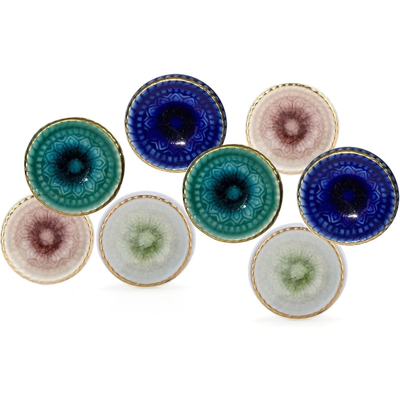 May include: A collection of eight small, decorative ceramic bowls in various colors, including teal, blue, pink, and green. Each bowl features a detailed, embossed pattern and a gold-colored rim. The bowls are arranged on a white background.