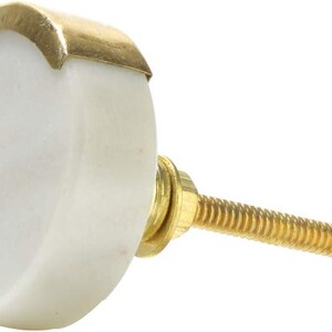 May include: A white marble cabinet knob with a gold-colored metal accent. The knob has a rounded shape and a threaded brass screw for installation. This decorative hardware is suitable for drawers and cabinets.