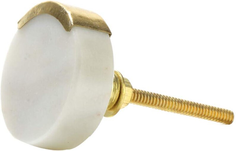 May include: A white marble cabinet knob with a gold-colored metal accent. The knob has a rounded shape and a threaded brass screw for installation. This decorative hardware is suitable for drawers and cabinets.
