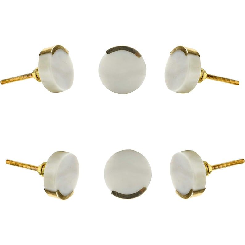 May include: Six white cabinet knobs with gold-colored accents. The knobs have a round, marble-like appearance and are attached to gold-colored screws. The knobs are arranged in a symmetrical pattern against a white background.