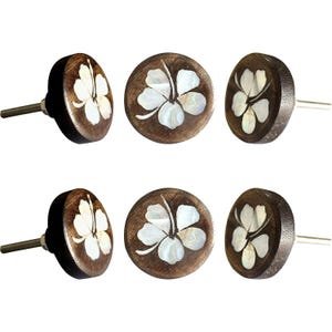 May include: Six wooden cabinet knobs with a dark brown finish and a white flower inlay. The knobs have a round shape with a metal screw for installation. The flower design is made of white mother-of-pearl.