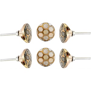 Pode incluir: Seis puxadores decorativos para armários. Os puxadores têm uma base dourada com incrustações de madrepérola e um padrão hexagonal. Os puxadores têm um parafuso prateado para instalação. Os puxadores estão dispostos em um padrão circular.