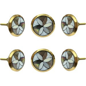 May include: Six decorative cabinet knobs with a floral design. Each knob features a gold-colored rim and stem, surrounding a mosaic of white, gray, and brown petal shapes. The knobs are arranged in two rows of three.