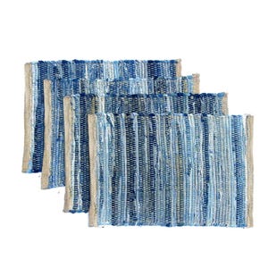 May include: Four rectangular placemats in shades of blue and beige. The placemats have a woven texture with vertical stripes of varying blue hues and beige edges. The placemats are stacked on top of each other.
