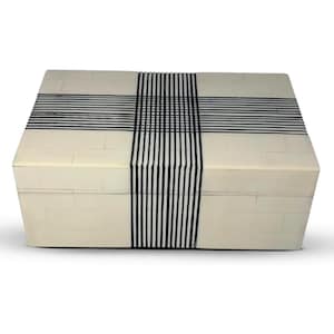 Puede incluir: Una caja rectangular con una superficie de color crema compuesta por pequeños segmentos en mosaico. Una prominente banda vertical y horizontal de finas líneas negras paralelas se cruza en el centro, creando un patrón de cuadrícula audaz.